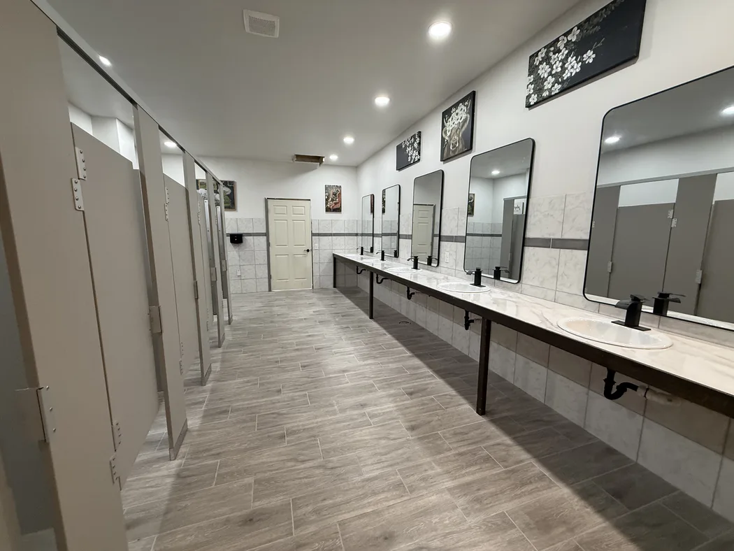The bathhouse: private stalls along one wall, a long vanity along the other