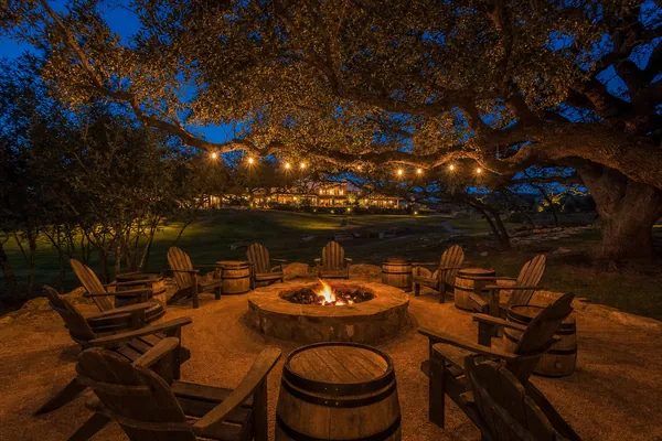 The fire pit commons under the string lights at dusk