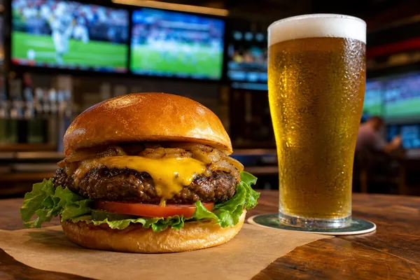 A cheeseburger and a pint at a sports bar